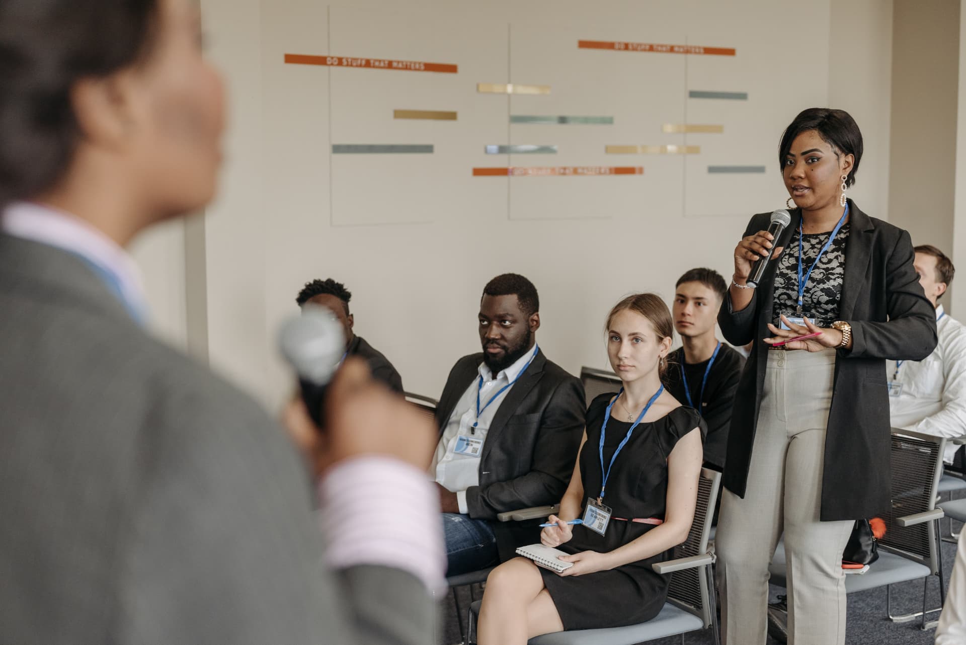 A guest standing with a microphone to ask a question during a session.