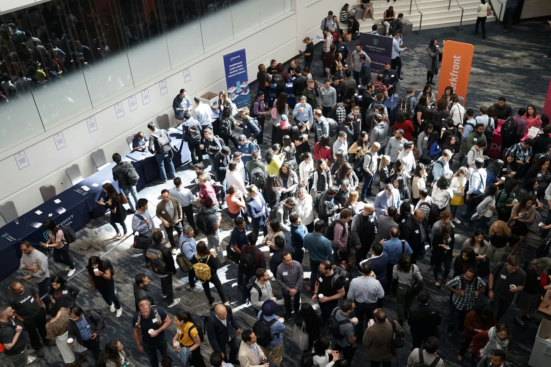 An overhead view of professionals talking in a busy conference reception.